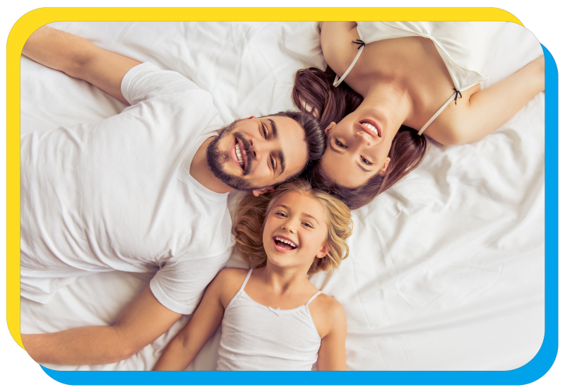 husband, wife, amd daughter posing on bed smiling