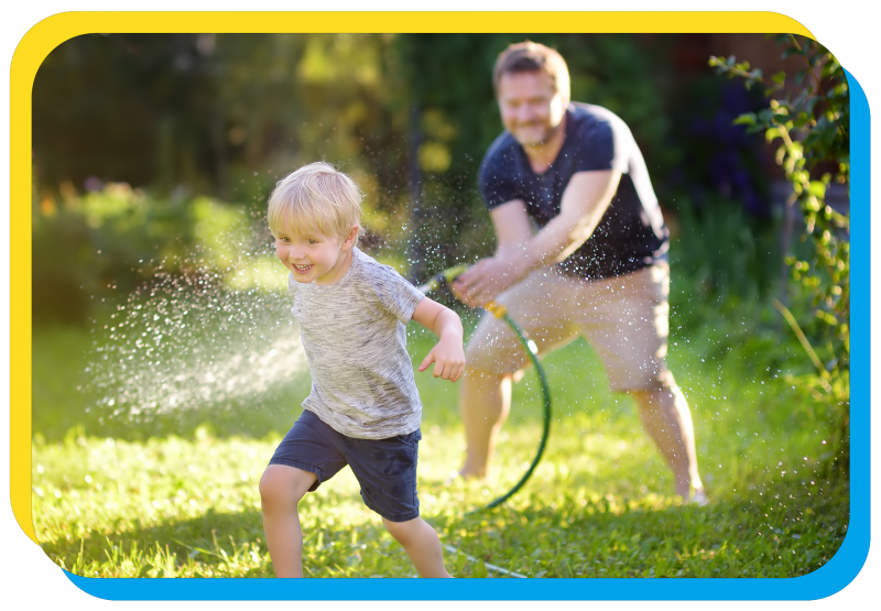 father spraying son with hose